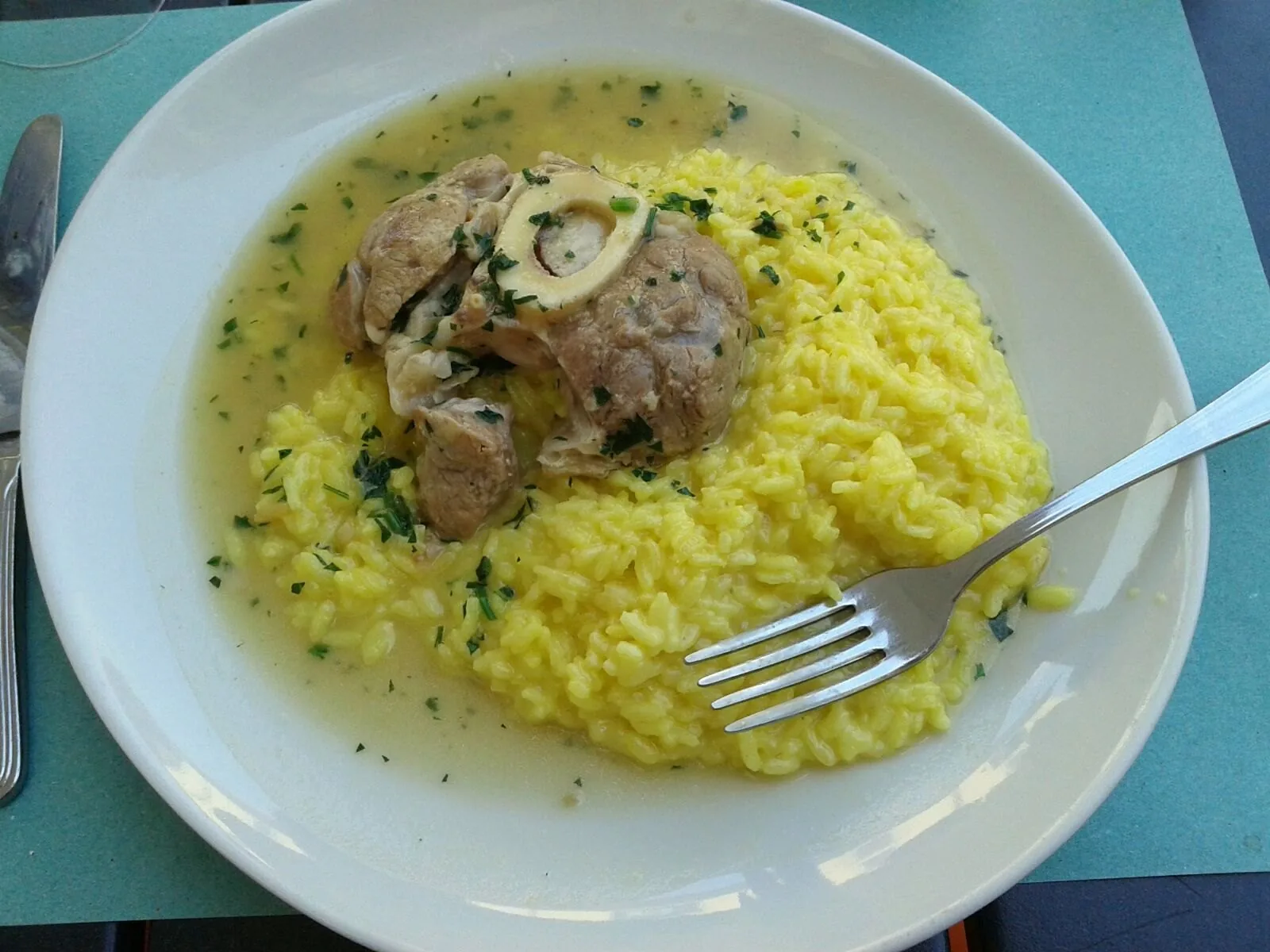 Un piatto di risotto alla milanese servito con ossobuco